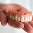 A closeup of a hand carefully holding a denture