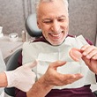 A dentist showing dentures to her older patient