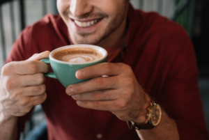 Close up of man smiling while he enjoys a latte